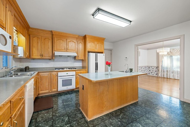 kitchen with sink, white appliances, and an island with sink