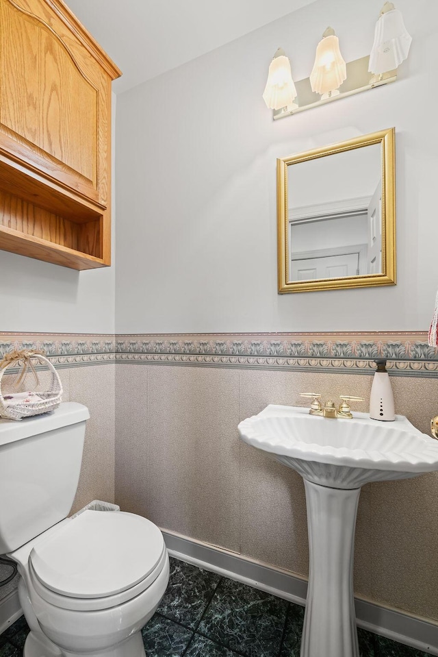 bathroom featuring sink, toilet, and tile walls