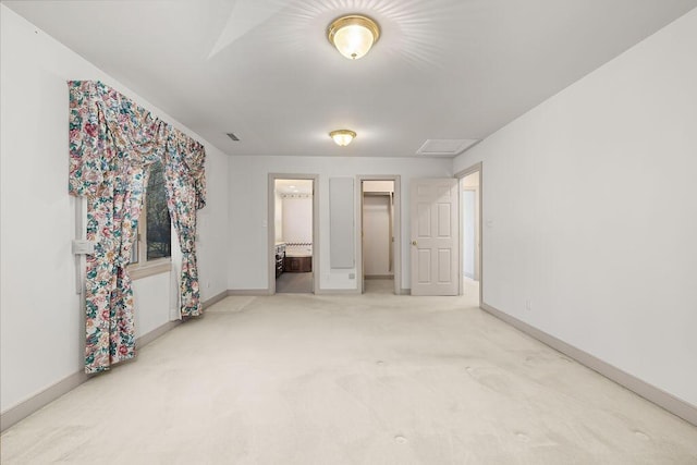 unfurnished bedroom featuring a walk in closet, light carpet, and ensuite bath