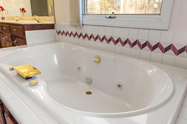 bathroom featuring tiled tub and vanity