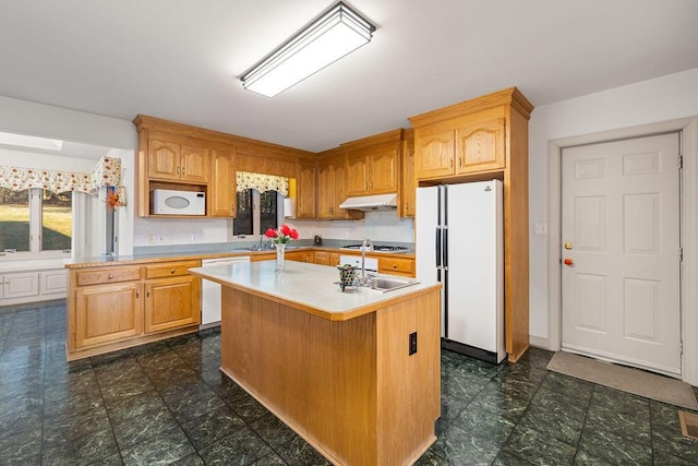 kitchen with sink, white appliances, and an island with sink