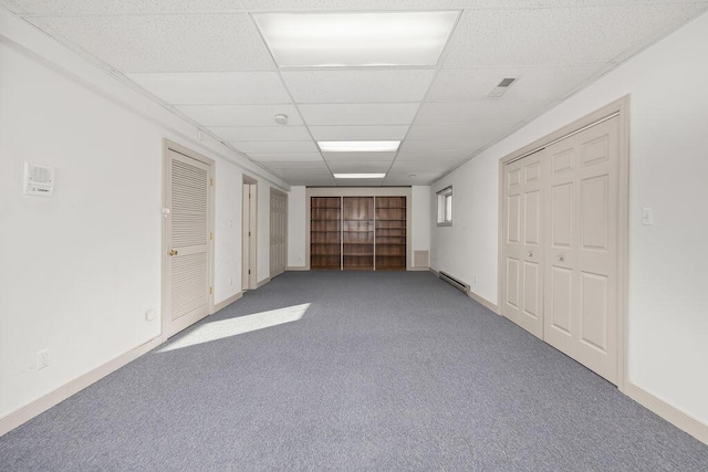 carpeted empty room featuring a paneled ceiling and a baseboard radiator