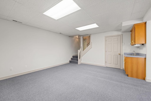 basement with sink, a paneled ceiling, and carpet floors