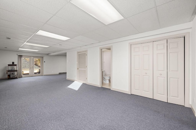 basement with a baseboard radiator, a drop ceiling, french doors, and carpet flooring