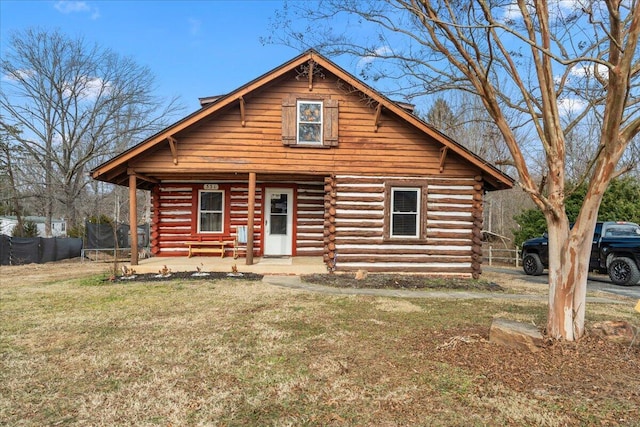 log cabin featuring a trampoline, a front yard, and a porch