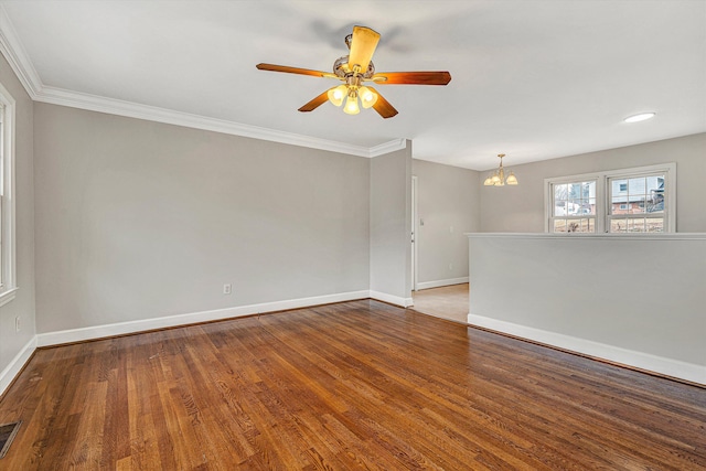 empty room with hardwood / wood-style flooring, crown molding, and ceiling fan with notable chandelier