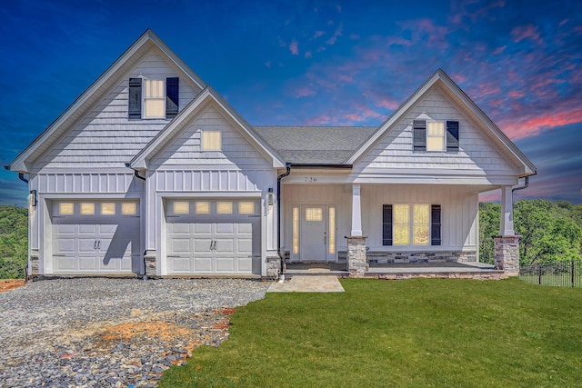 view of front of house with gravel driveway, board and batten siding, covered porch, stone siding, and an attached garage