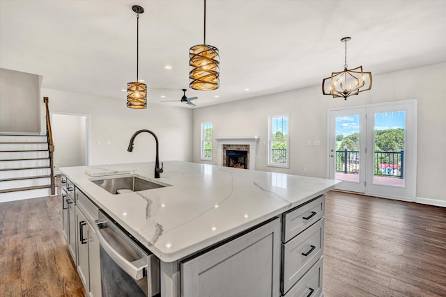 kitchen with a sink, dishwasher, open floor plan, a fireplace, and dark wood-style flooring