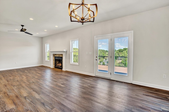 unfurnished living room featuring dark wood-style floors, recessed lighting, baseboards, a chandelier, and a fireplace