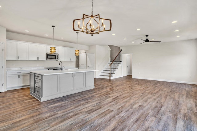 kitchen featuring stainless steel microwave, recessed lighting, a ceiling fan, dark wood finished floors, and light countertops