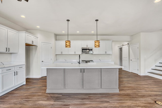 kitchen featuring stainless steel microwave, baseboards, recessed lighting, a barn door, and white cabinets