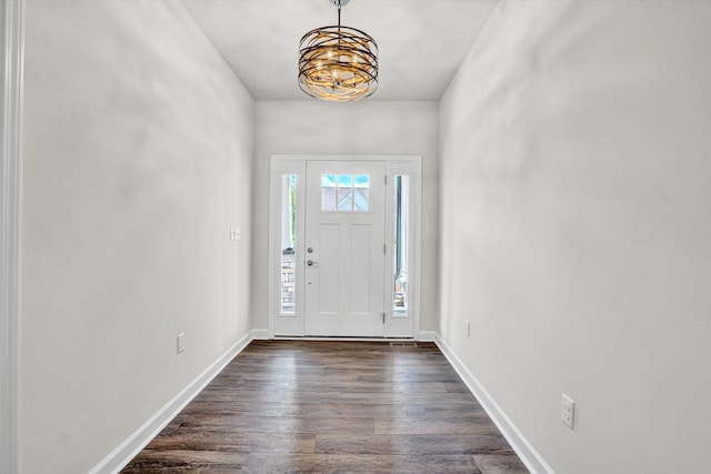 entrance foyer with a chandelier, dark wood-style floors, and baseboards