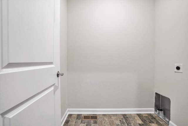 clothes washing area with hookup for an electric dryer, dark wood-style floors, and baseboards