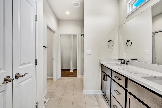 bathroom featuring baseboards, marble finish floors, and double vanity