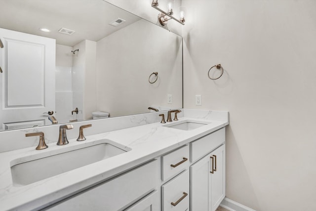 full bathroom featuring double vanity, a shower, and toilet