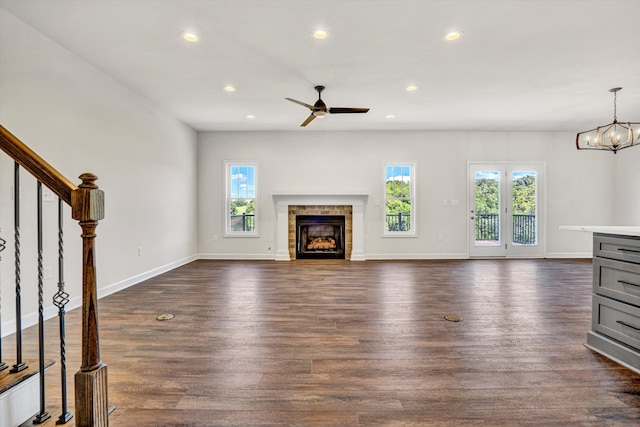 unfurnished living room featuring healthy amount of natural light, a tiled fireplace, a ceiling fan, dark wood-style flooring, and recessed lighting