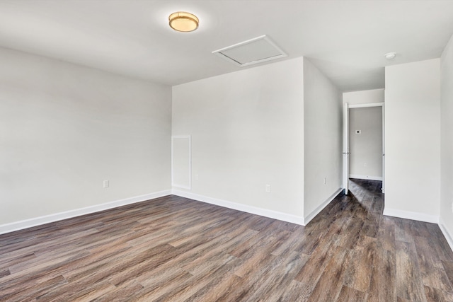 spare room with wood finished floors, attic access, and baseboards
