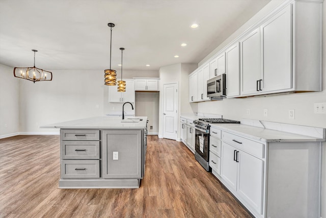 kitchen with appliances with stainless steel finishes, light wood finished floors, a sink, baseboards, and recessed lighting