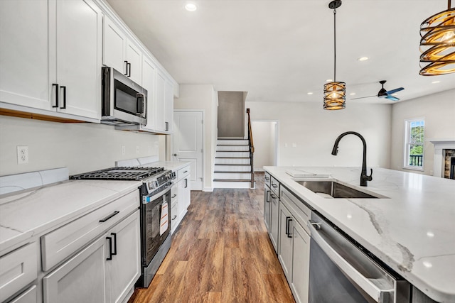 kitchen with appliances with stainless steel finishes, a sink, ceiling fan, wood finished floors, and pendant lighting