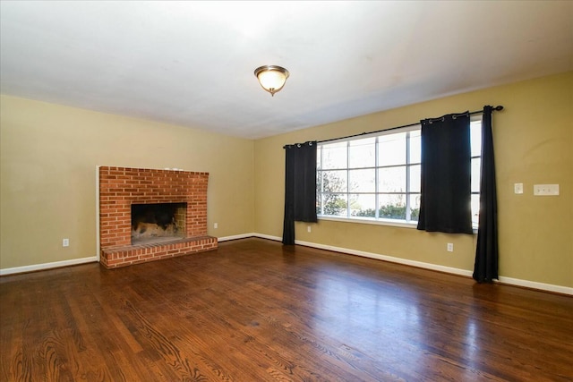 unfurnished living room with dark hardwood / wood-style flooring and a brick fireplace