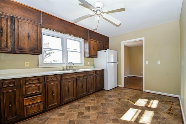 kitchen with ceiling fan, dark brown cabinets, sink, and white fridge