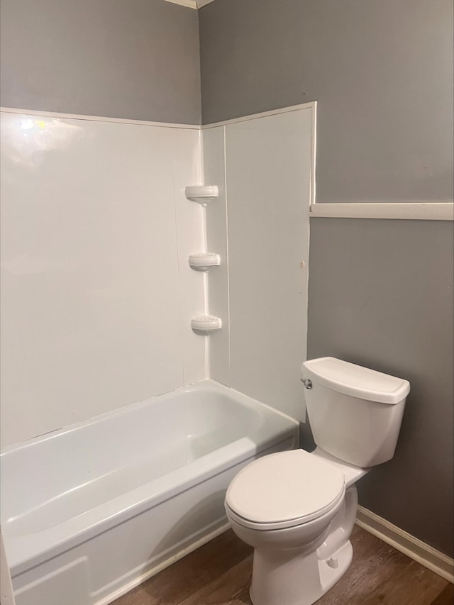 bathroom featuring wood-type flooring, tub / shower combination, and toilet