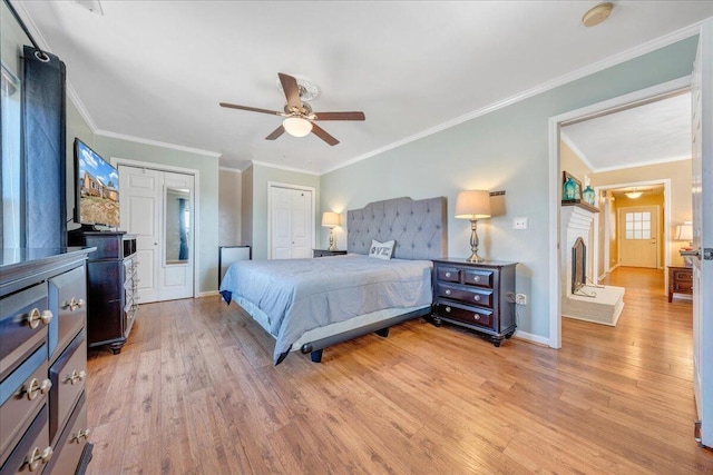 bedroom featuring ceiling fan, ornamental molding, light hardwood / wood-style floors, and a brick fireplace