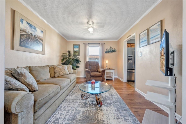 living room with ceiling fan, crown molding, wood-type flooring, and a textured ceiling