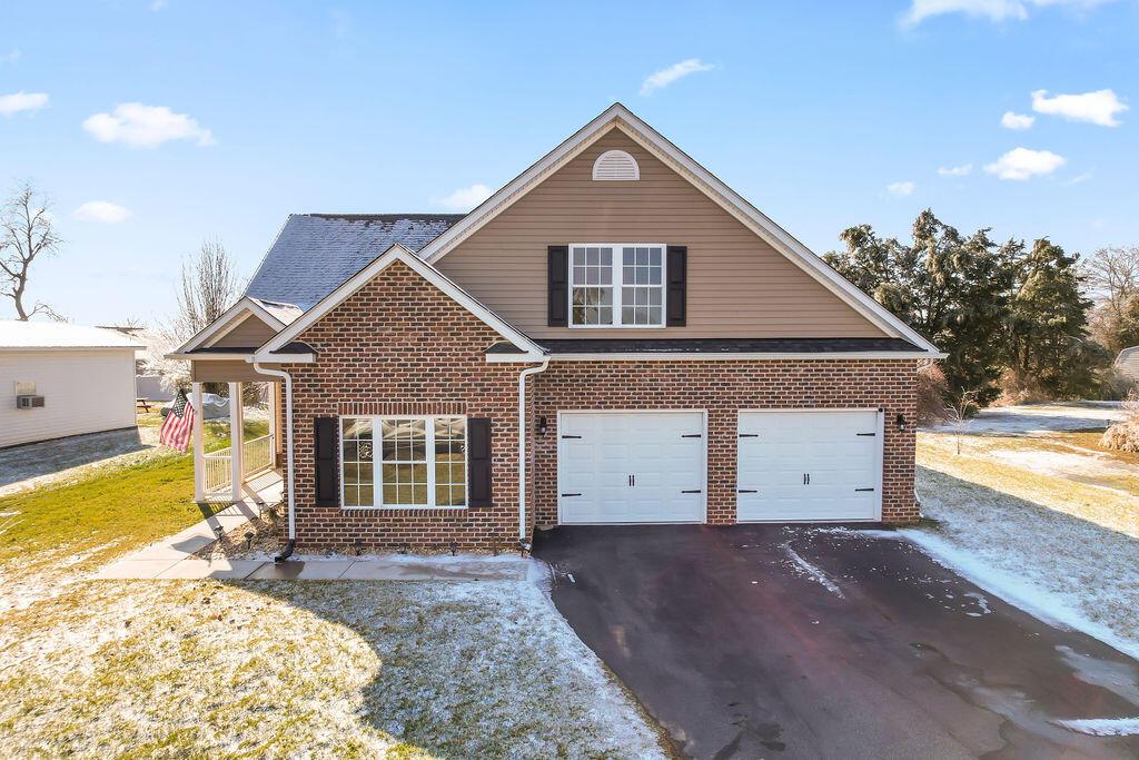 traditional-style home featuring a garage, driveway, and brick siding