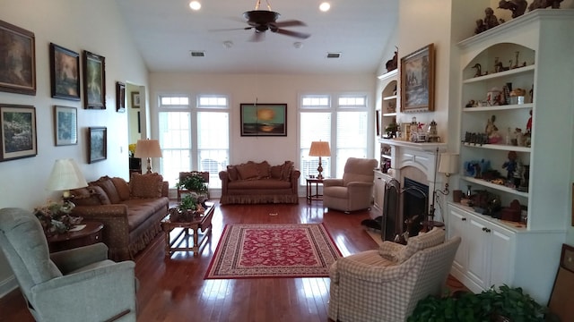 living area featuring lofted ceiling, visible vents, a fireplace, and hardwood / wood-style floors