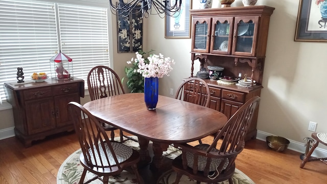 dining space with light wood finished floors, baseboards, and a chandelier