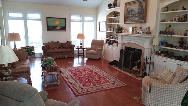 living area featuring a fireplace with flush hearth, wood finished floors, lofted ceiling, and a healthy amount of sunlight