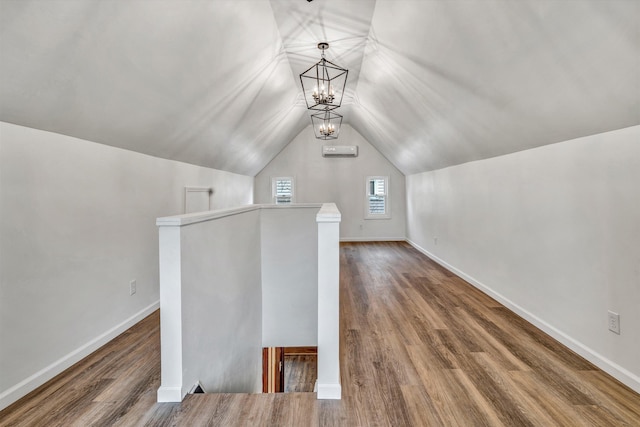 additional living space featuring lofted ceiling, hardwood / wood-style floors, and a chandelier