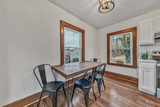 dining room featuring dark wood-type flooring, plenty of natural light, and a chandelier