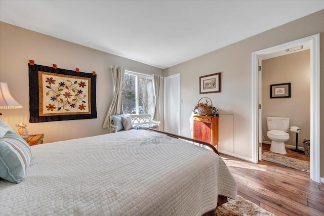 bedroom with ensuite bath and hardwood / wood-style floors