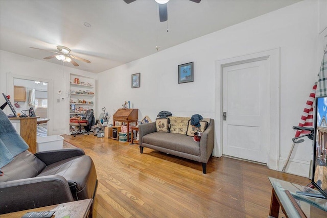 living room featuring wood-type flooring, built in features, and ceiling fan