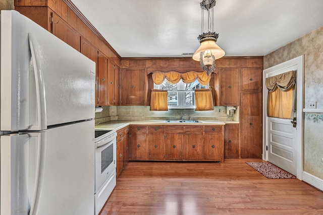 kitchen featuring pendant lighting, sink, white appliances, decorative backsplash, and light wood-type flooring