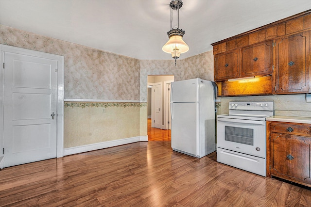 kitchen featuring pendant lighting, white appliances, and light hardwood / wood-style flooring