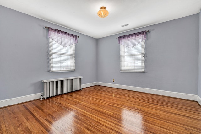 spare room featuring radiator heating unit and wood-type flooring