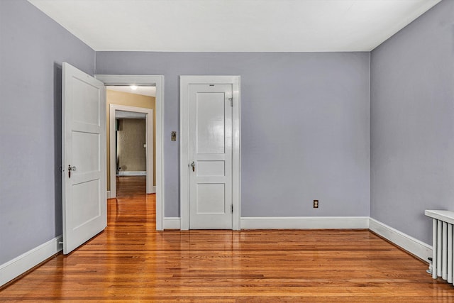 empty room with radiator heating unit and light hardwood / wood-style floors