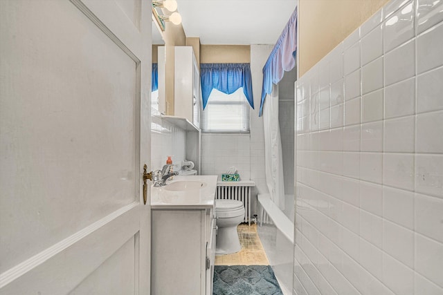 full bathroom with radiator, tile walls, vanity, shower / tub combo, and toilet