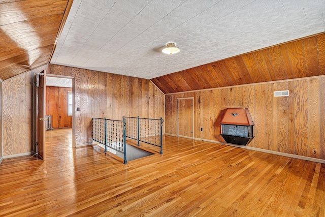 additional living space with radiator, vaulted ceiling, and hardwood / wood-style floors