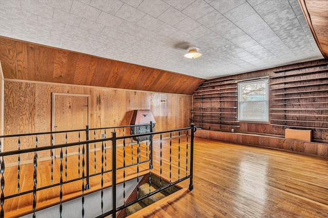 bonus room with hardwood / wood-style flooring, vaulted ceiling, and wood walls