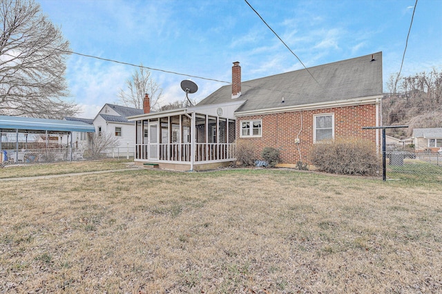 rear view of house featuring a lawn and a sunroom