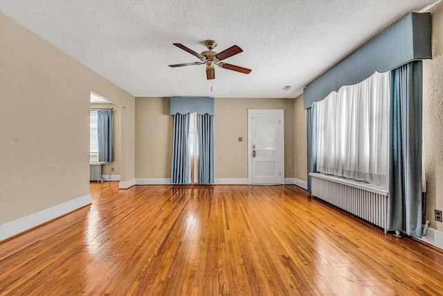 empty room featuring light hardwood / wood-style flooring, radiator heating unit, and a textured ceiling