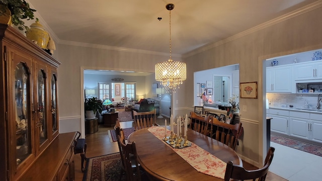 dining area featuring crown molding, sink, and a notable chandelier