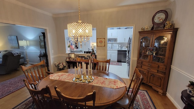 dining area featuring ornamental molding, hardwood / wood-style floors, and a notable chandelier