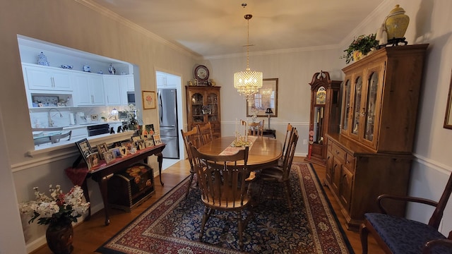 dining room with a notable chandelier, light hardwood / wood-style flooring, ornamental molding, and sink