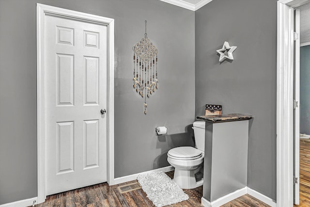 bathroom with visible vents, toilet, baseboards, and wood finished floors