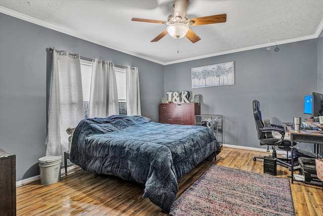 bedroom featuring a ceiling fan, a textured ceiling, wood-type flooring, crown molding, and baseboards